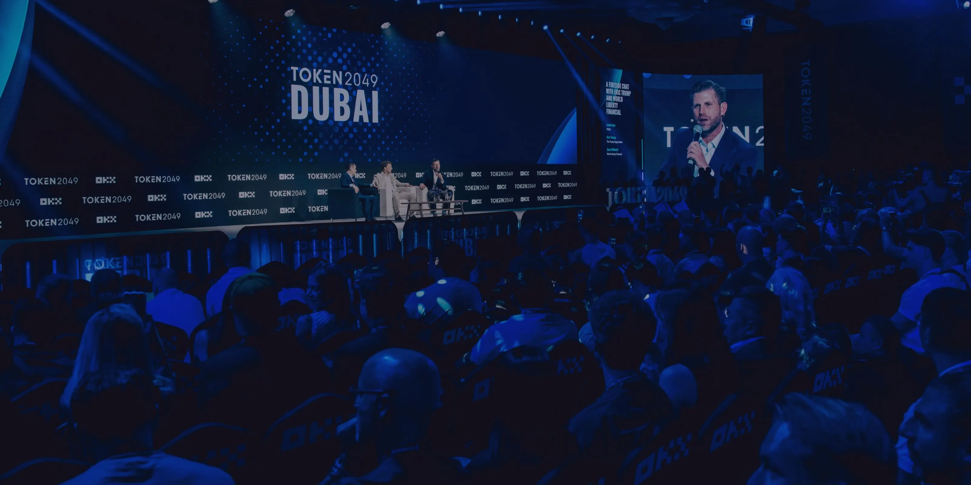 Changpeng Zhao, former CEO of Binance, speaking on stage at TOKEN2049 Dubai with a large audience and event branding in the background